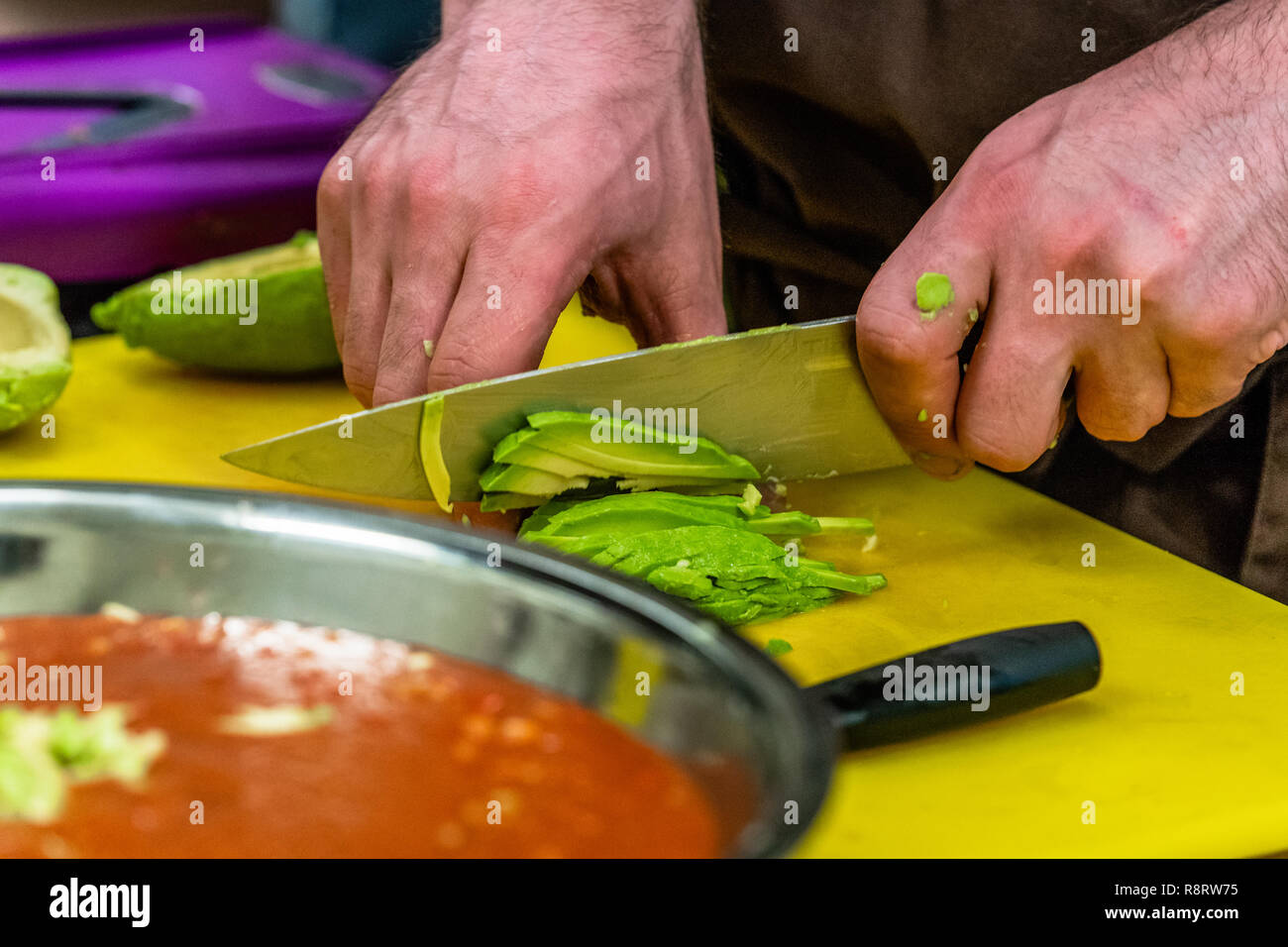 Male Chef Slicing Avocado for  Wedding Meal - Kitchen Set with Isolated Action, Only Chef`s Hands Stock Photo